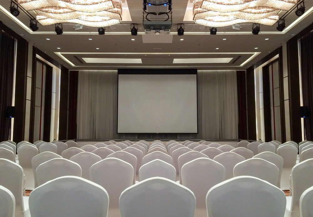 Rows of White Chairs Face a Blank Projector Screen in an Empty Auditorium — Coastal Vibez In Sydney, NSW