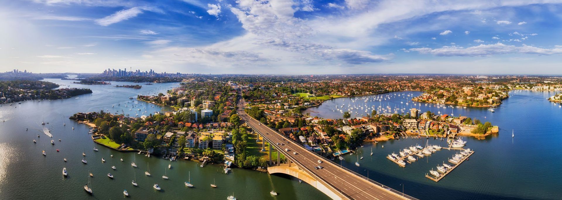 An aerial view of a bridge over a body of water surrounded by boats — Coastal Vibez In The Entrance, NSW