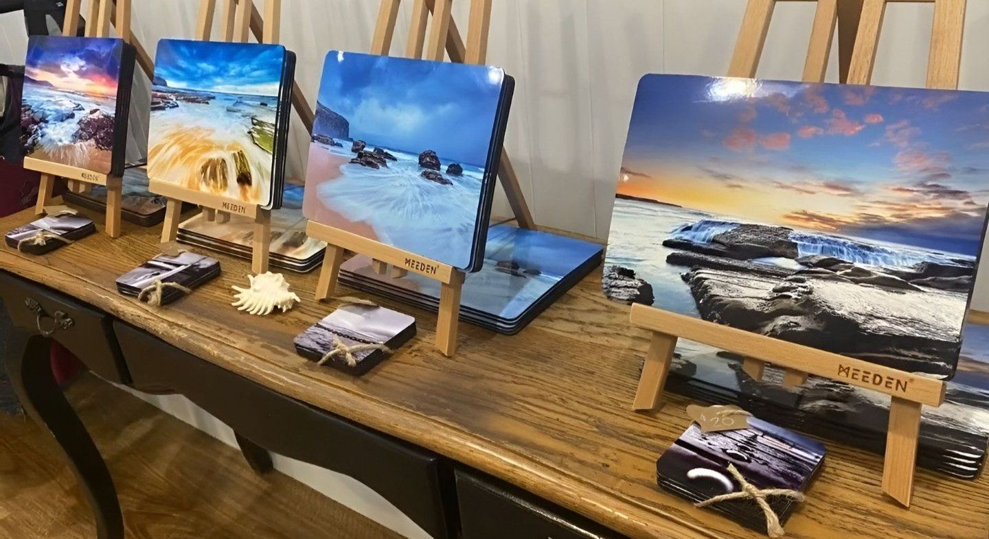 A Table With Paintings On Easels And Coasters On It  — Coastal Vibez In The Entrance, NSW