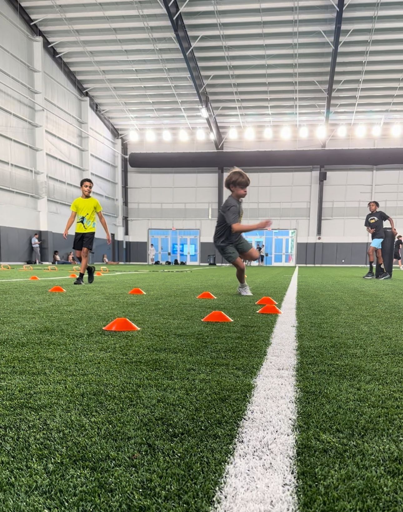 young footballer in blue sportswear at training session on grass soccer field