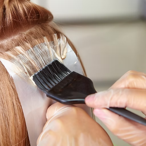 A woman is getting her hair dyed with a brush