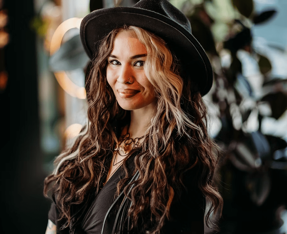 A woman wearing a hat and a necklace is smiling for the camera.