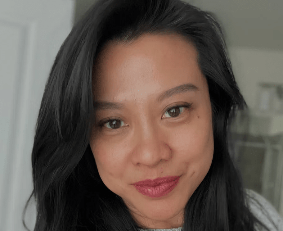 A close up of a woman 's face with long black hair and red lips.