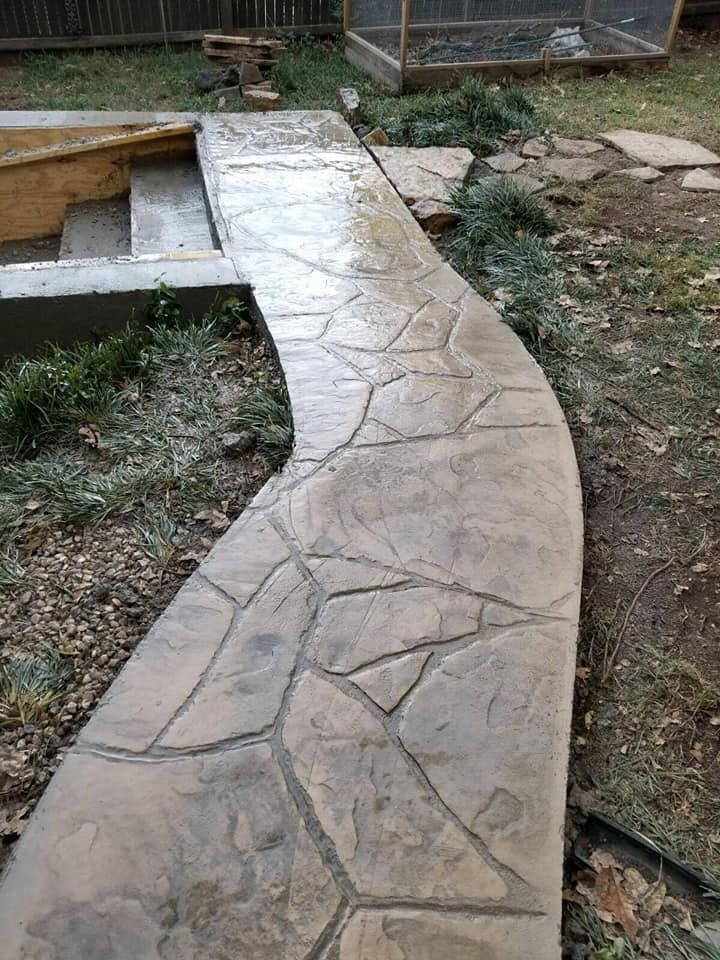 A concrete walkway leading to a pool in a backyard.