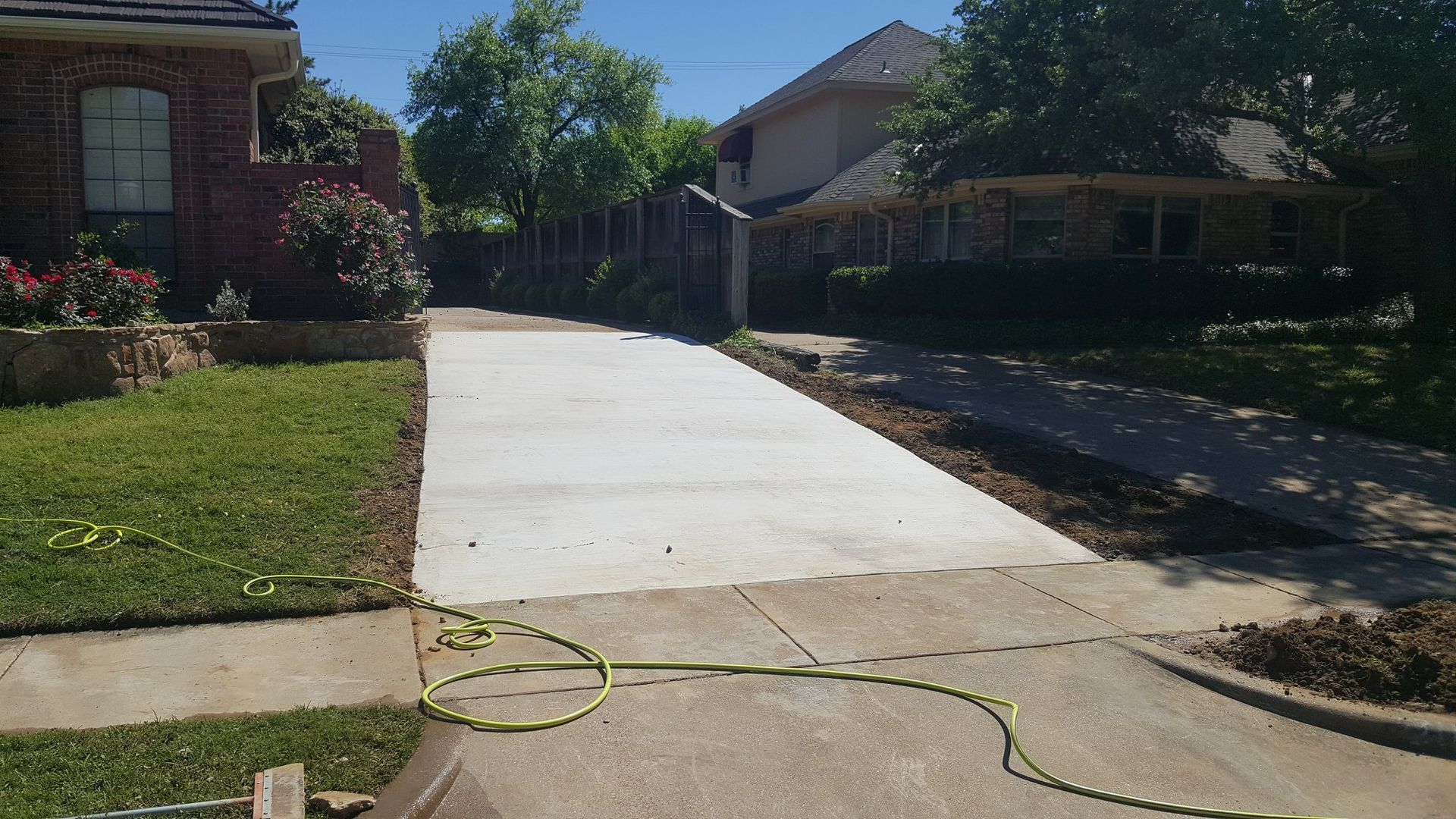 A concrete driveway is being built in front of a brick house.