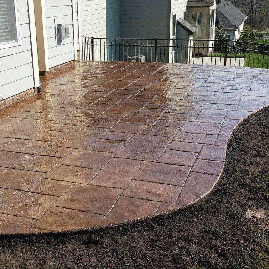 A patio in front of a house with a fence
