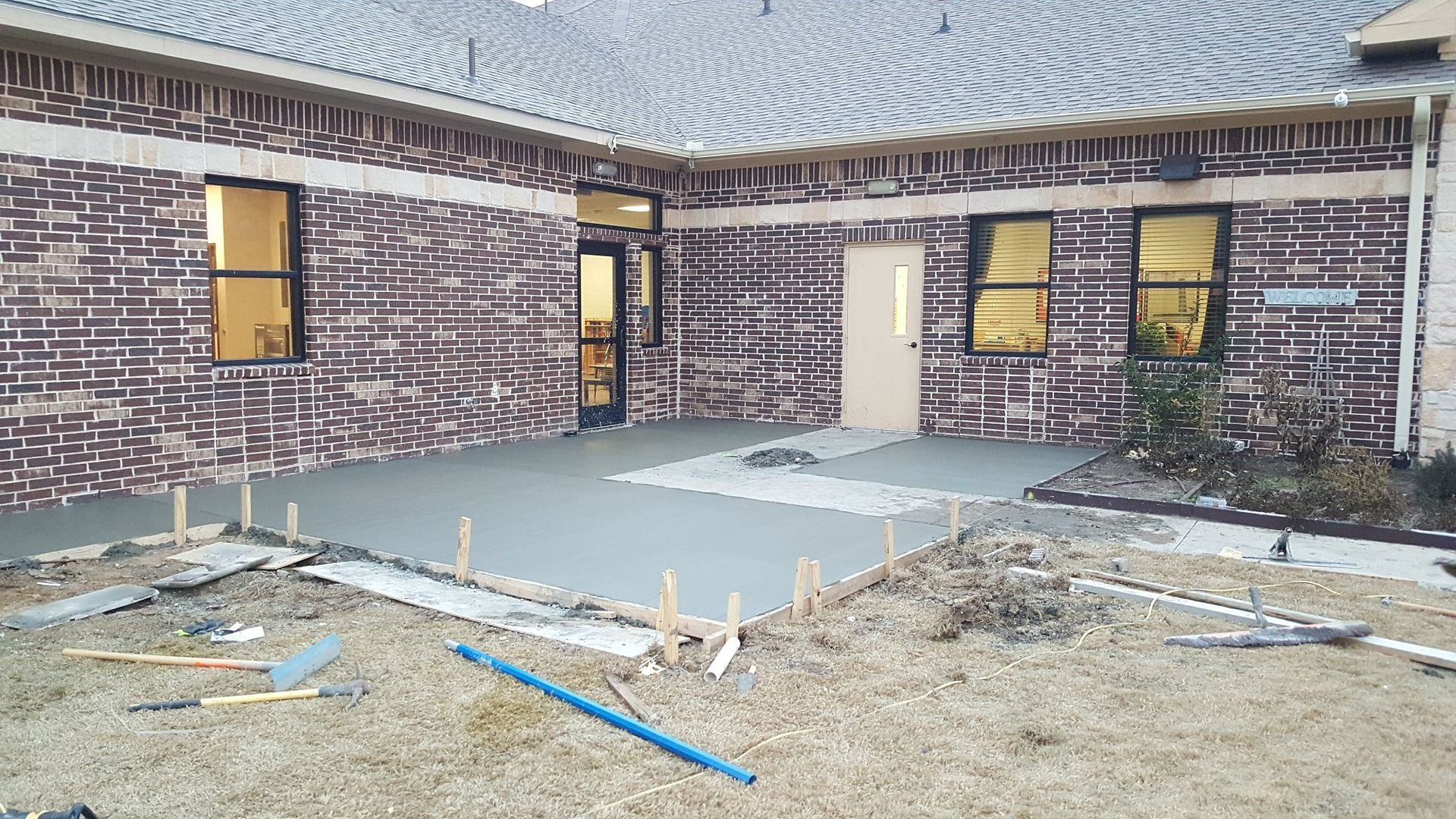 A brick building with a concrete walkway in front of it.