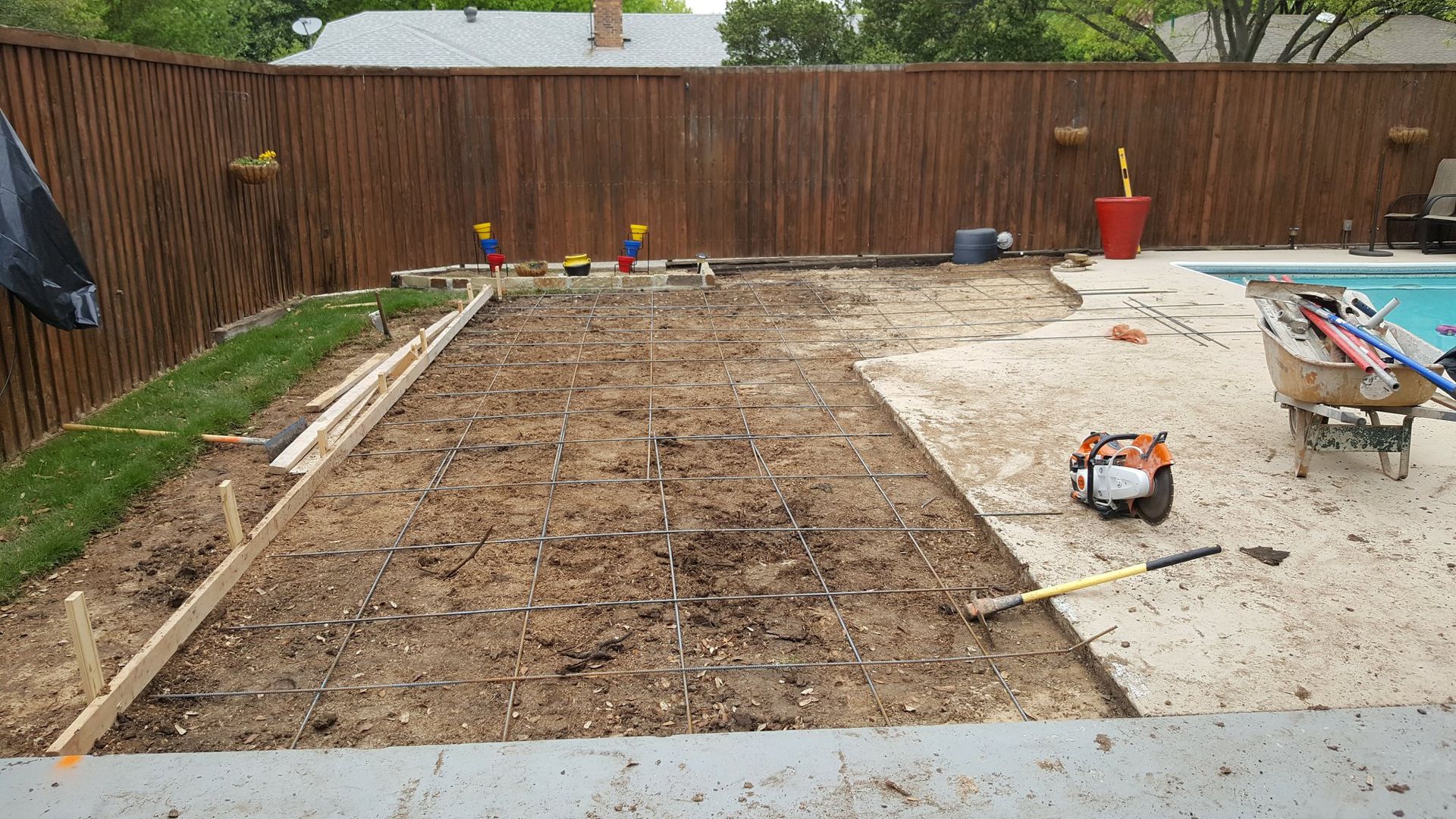 A concrete driveway is being built next to a pool