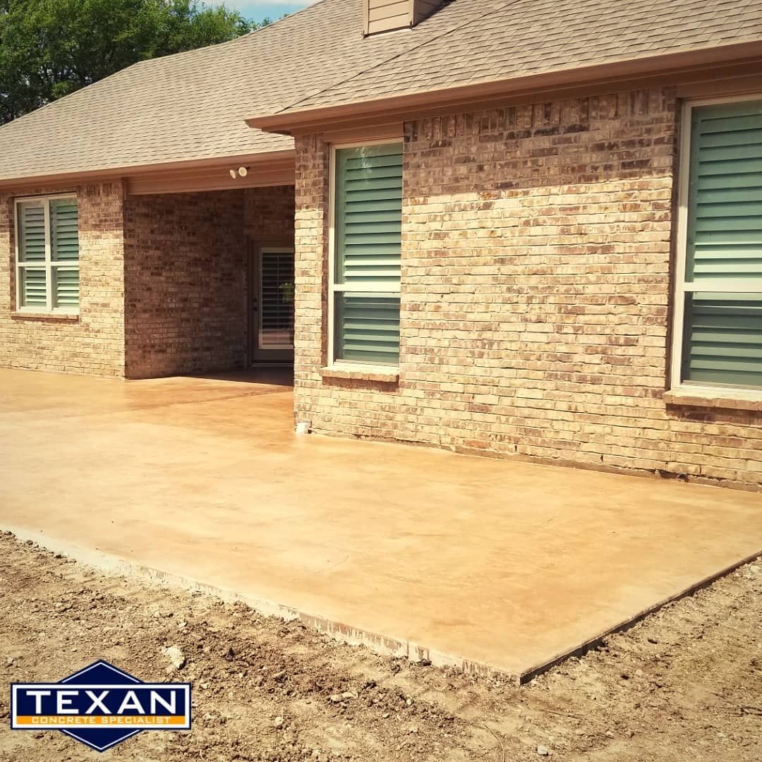 A brick house with a concrete driveway in front of it.