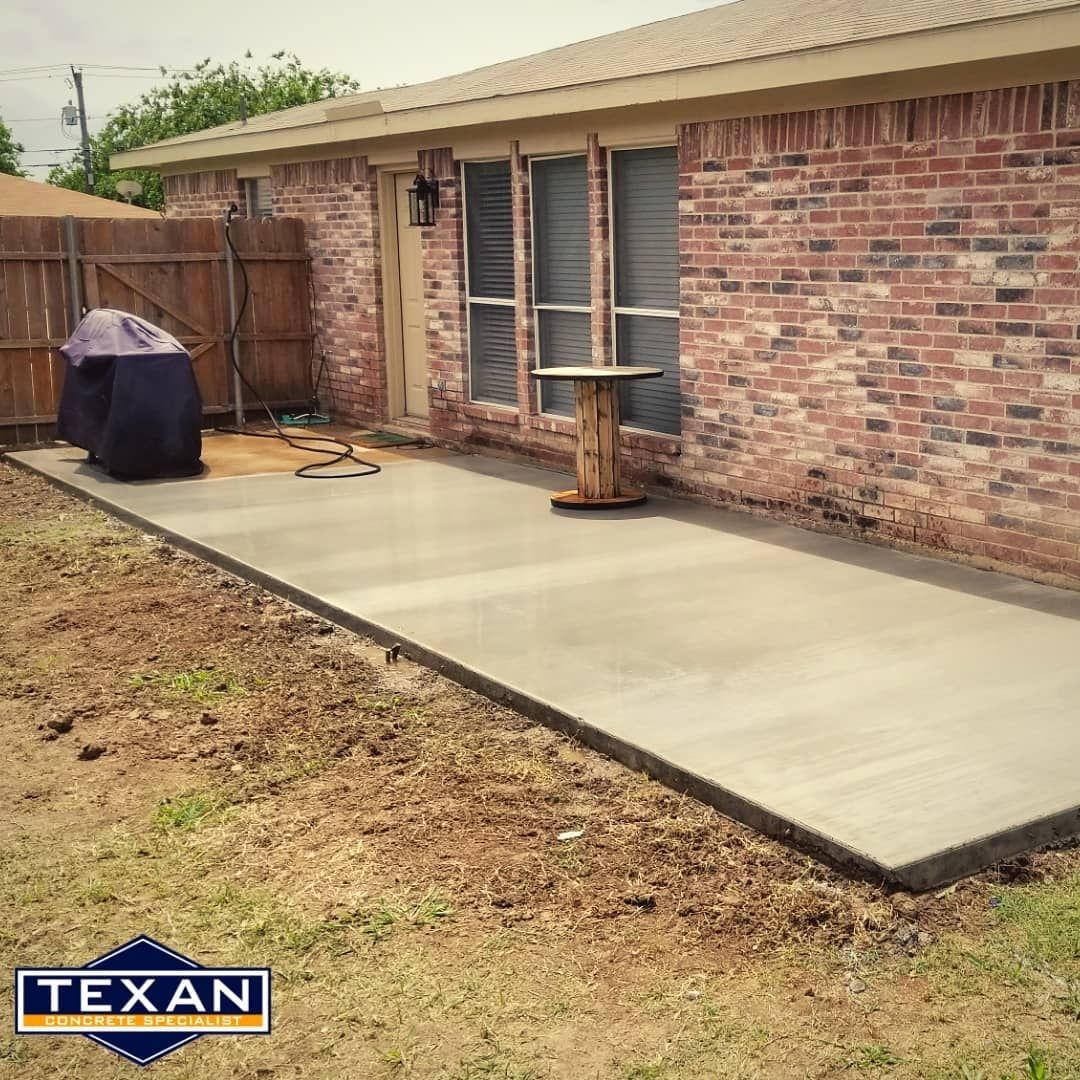 A brick house with a concrete patio in front of it