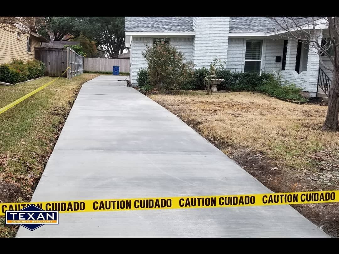 A concrete walkway leading to a house with caution tape on it