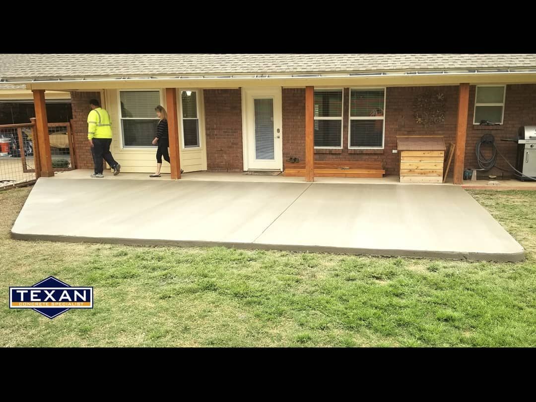 A concrete patio is being built in front of a brick house.