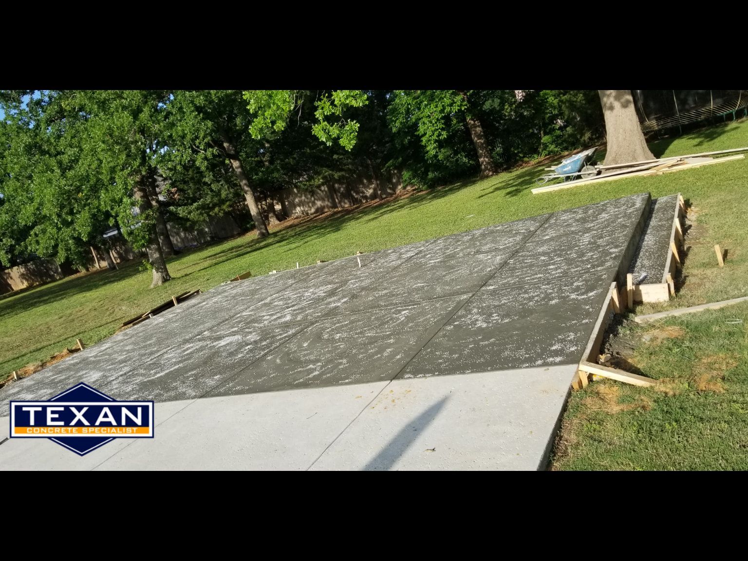 A concrete driveway is being built in a backyard.