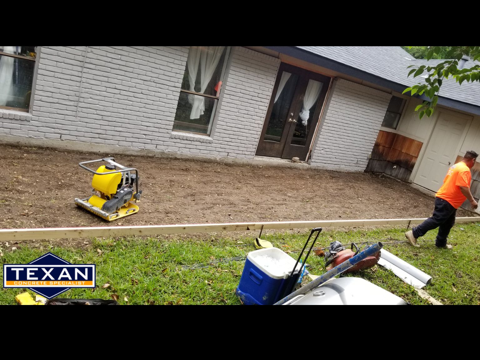 A man is working on a patio in front of a house.
