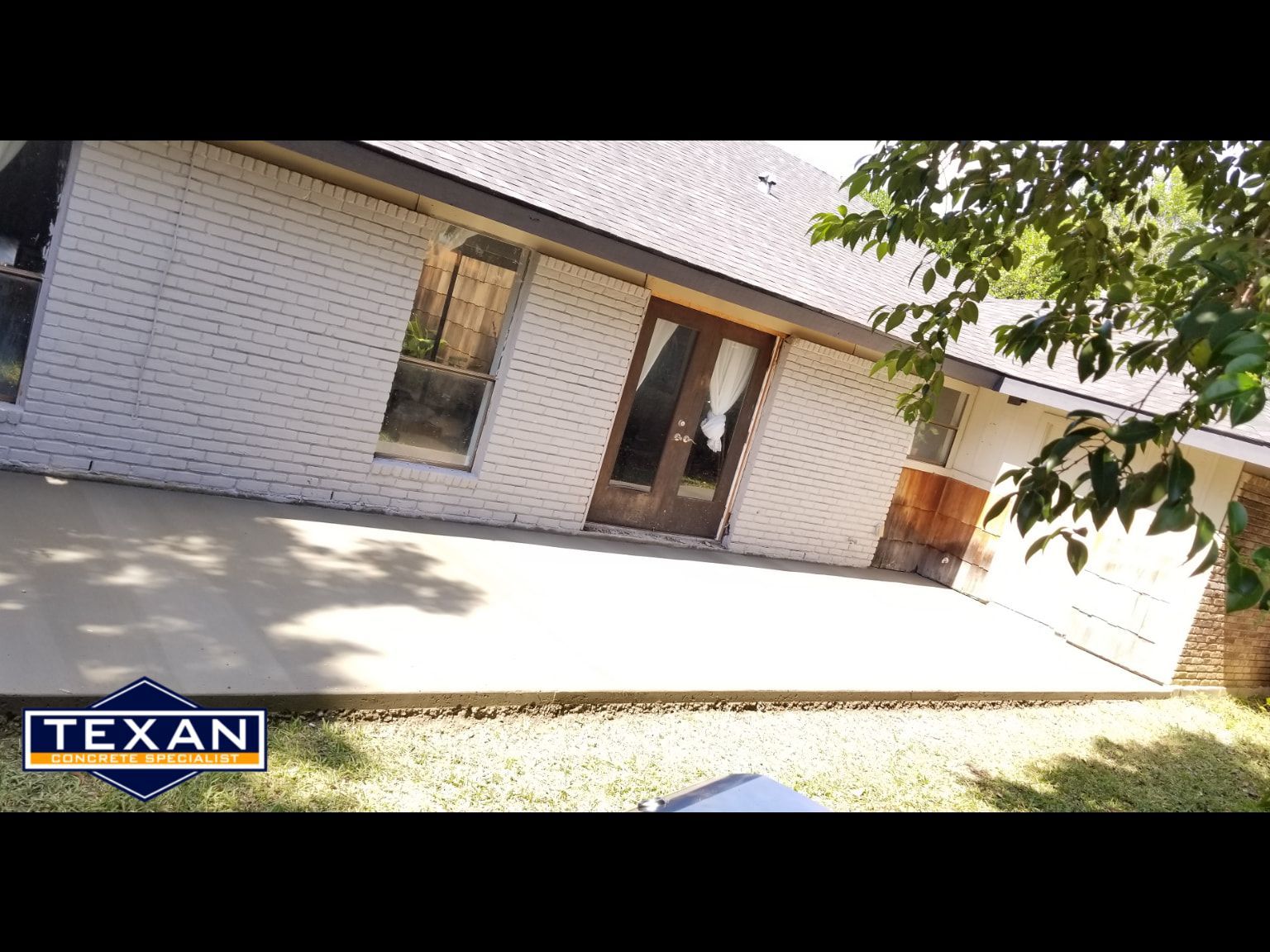 A white brick house with a patio in front of it