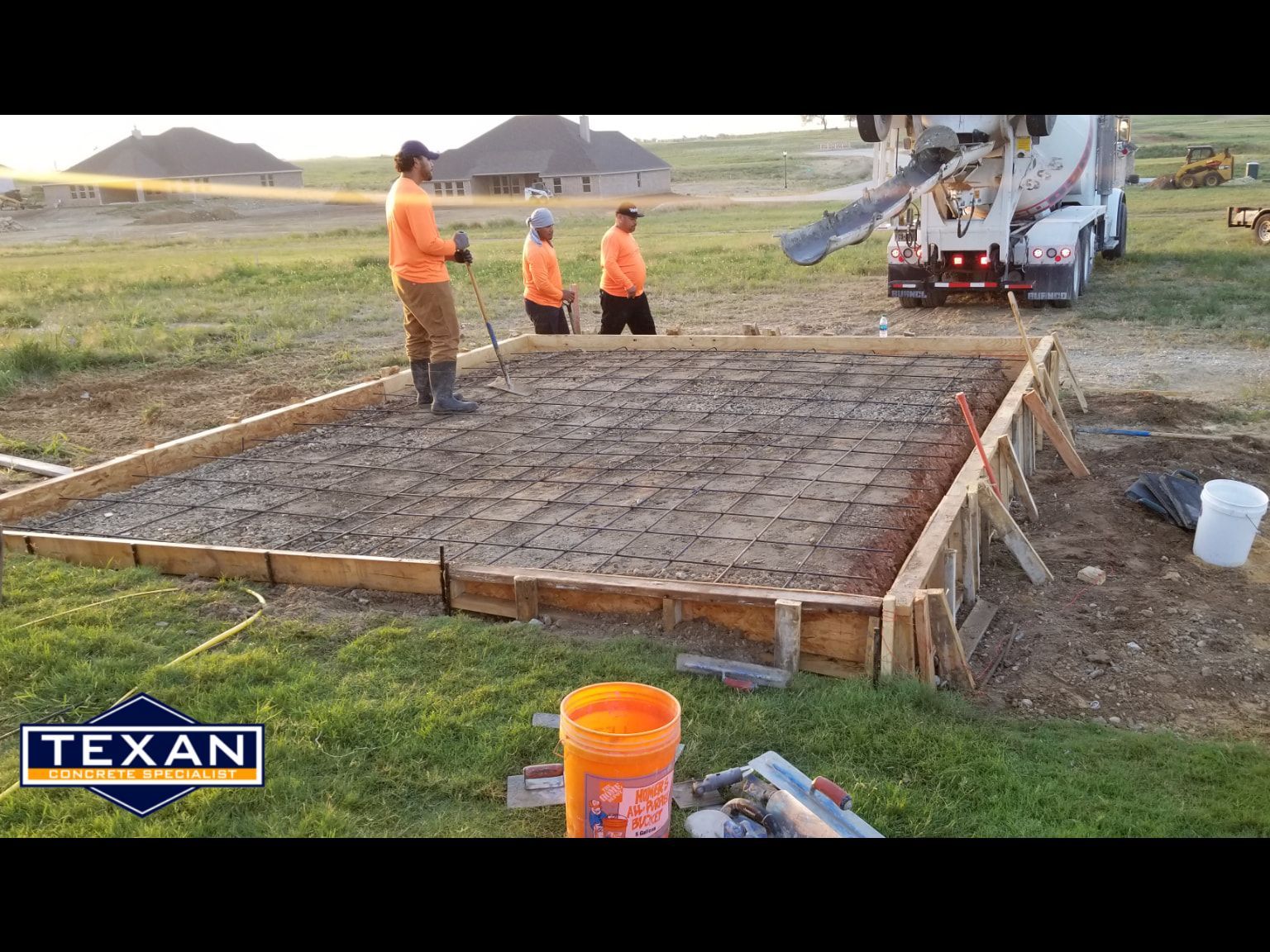 A concrete truck is pouring concrete into a concrete slab.