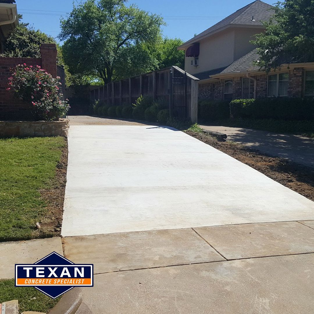 A concrete driveway with a texan logo on it