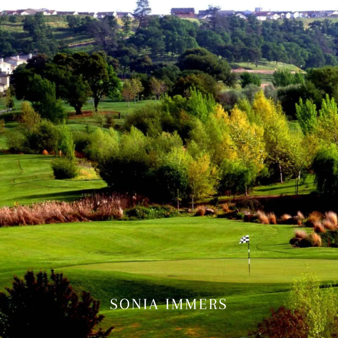 Sonia Immers - Immers Real Estate: Scenic Whitney Oaks golf course green with rolling hills, lush trees, and luxury homes.