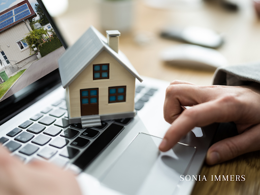 A person is using a laptop with a model house on the keyboard.