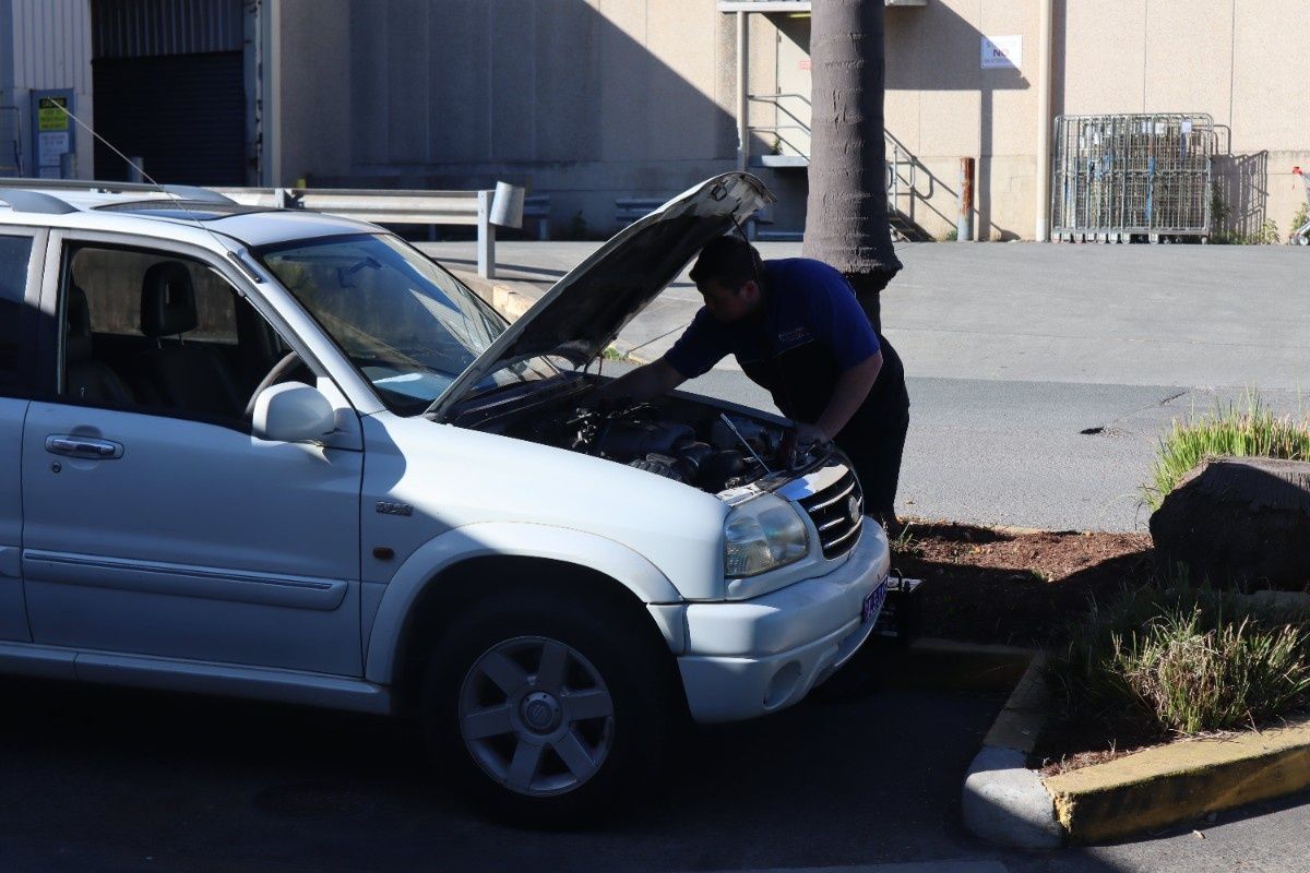 A man is looking under the hood of a white suv — Pacific Plaza Automotive in Port Macquarie, NSW