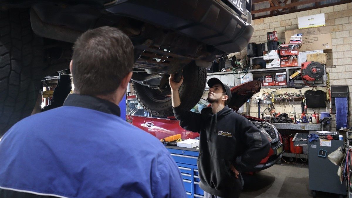 Two men are working on a car in a garage — Pacific Plaza Automotive in Port Macquarie, NSW