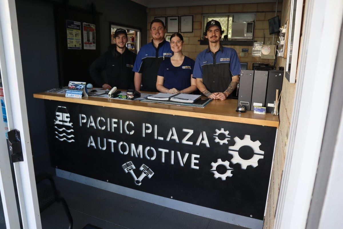 A group of people standing behind a counter at pacific plaza automotive — Pacific Plaza Automotive in Port Macquarie, NSW