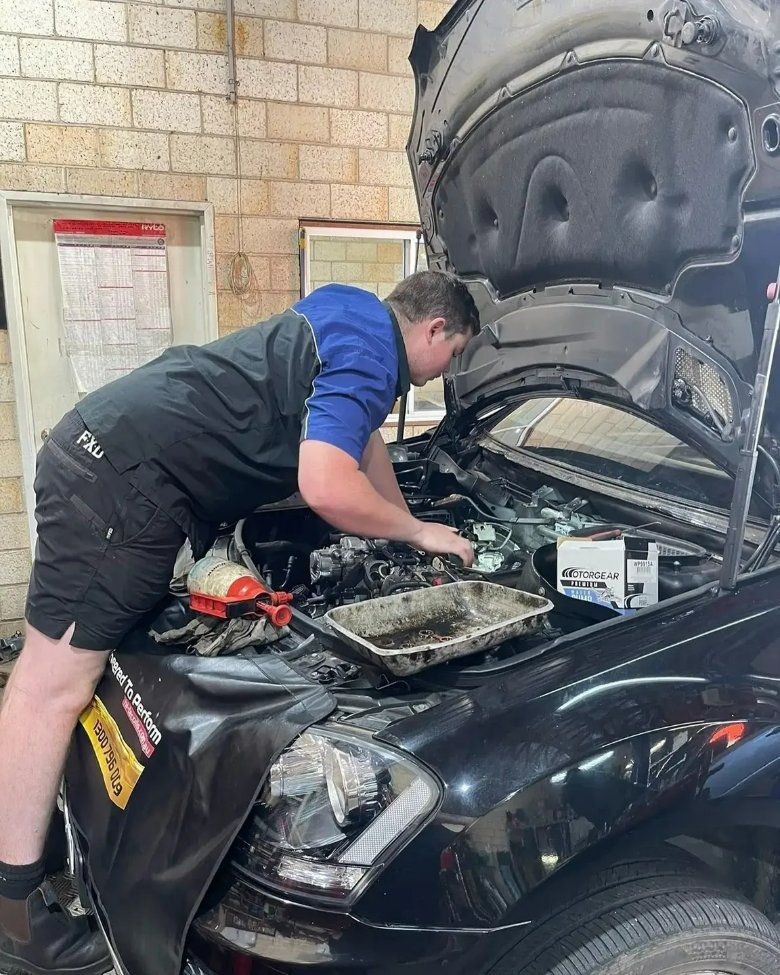 A man is working under the hood of a black car — Pacific Plaza Automotive in Port Macquarie, NSW