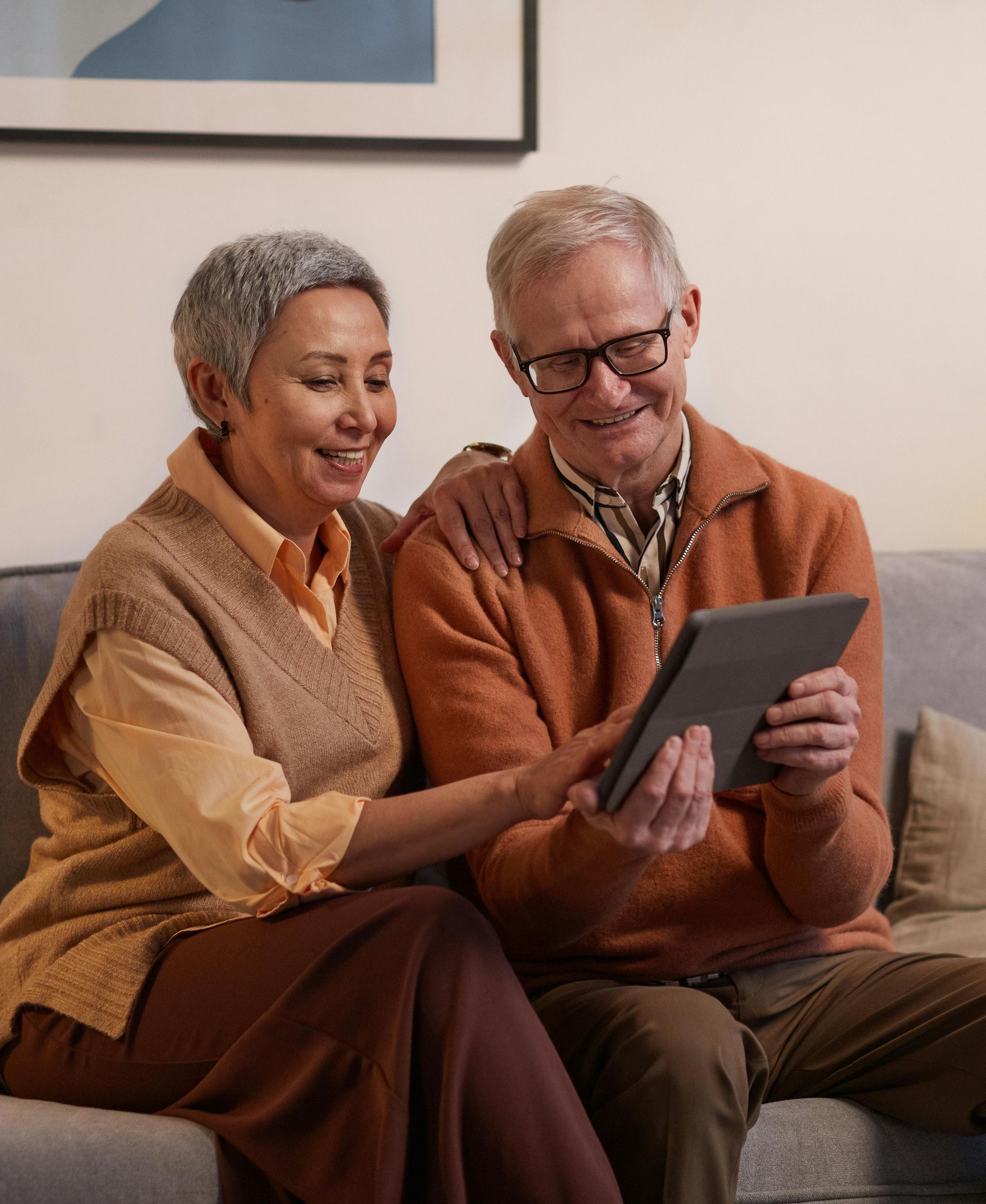 Senior couple sitting on a couch together looking at a tablet