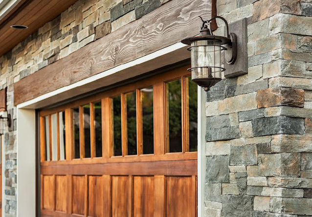 A Wooden Garage Door with A Light on The Side of A Stone Building - Rochester Hills, MI - J & B Doors