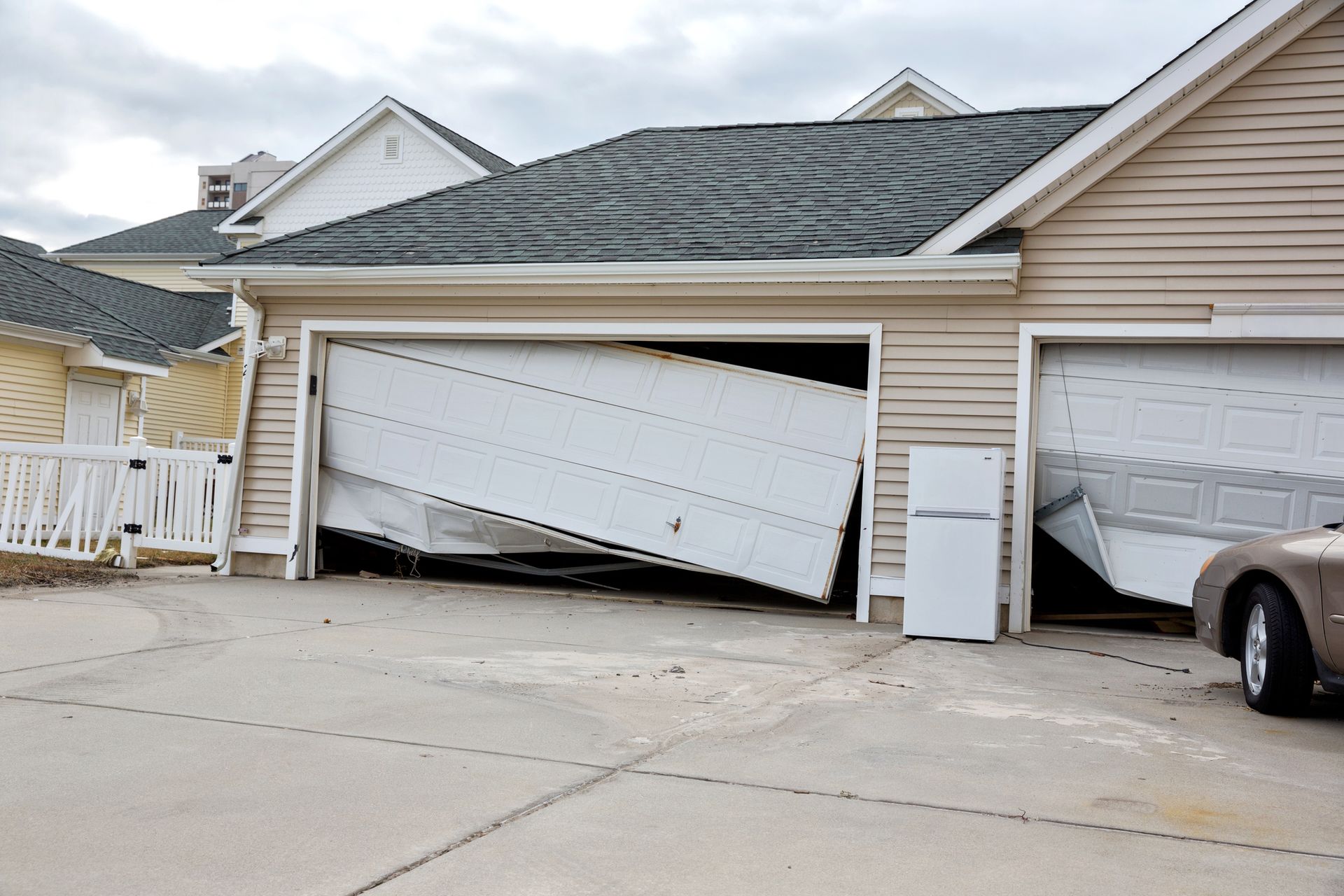 A Car Is Parked in Front of A House with A Broken Garage Door - Rochester Hills, MI - J & B Doors