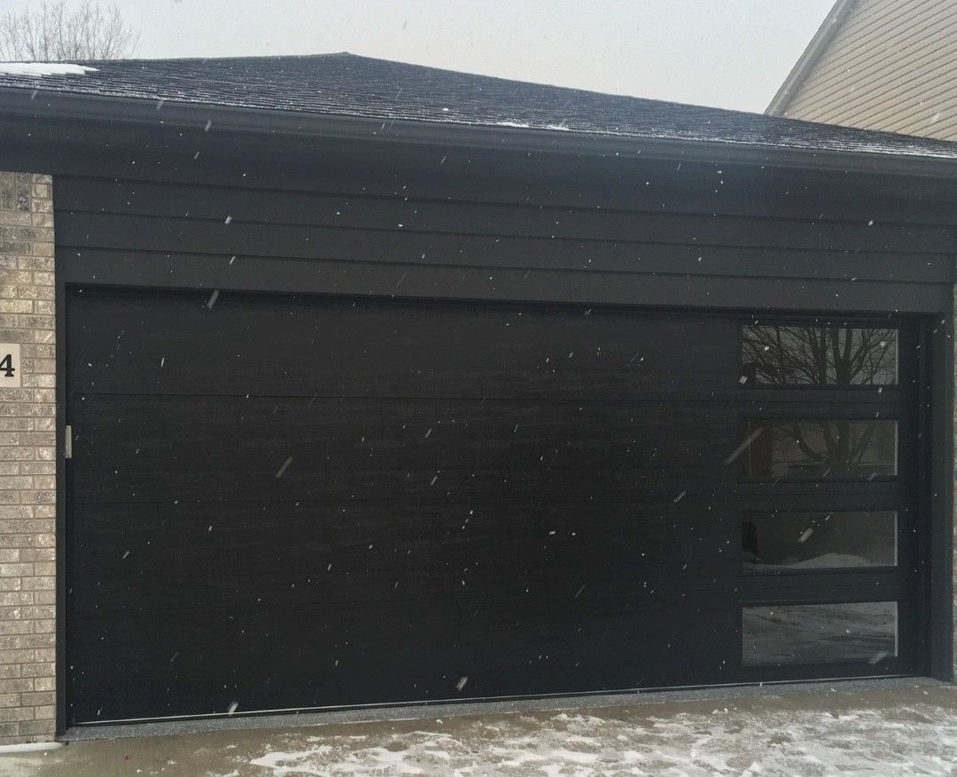 A Black Garage Door Is Sitting in Front of A House in The Snow - Rochester Hills, MI - J & B Doors