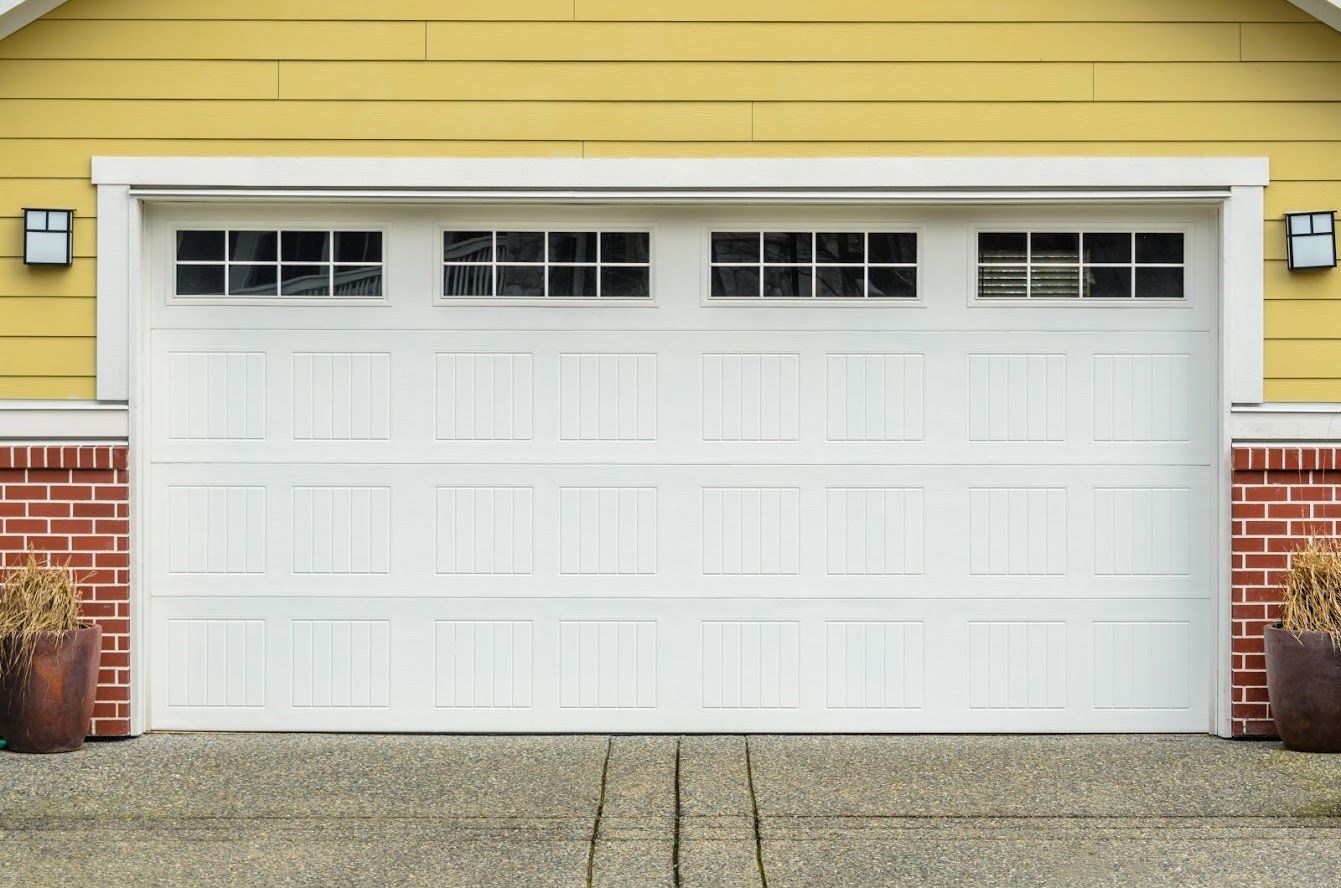 A White Garage Door Is Sitting in Front of A Yellow House - Rochester Hills, MI - J & B Doors