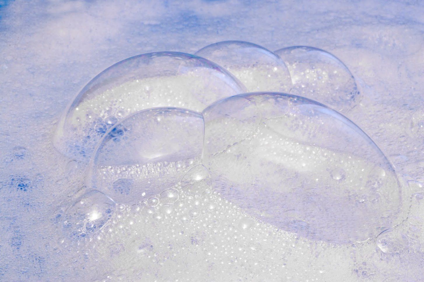 soap bubbles are floating in the water on a blue surface .