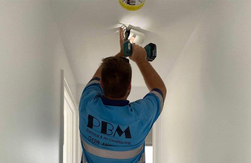 A Professional Installing A Smoke Detection Device — Electricians in the Whitsundays, QLD