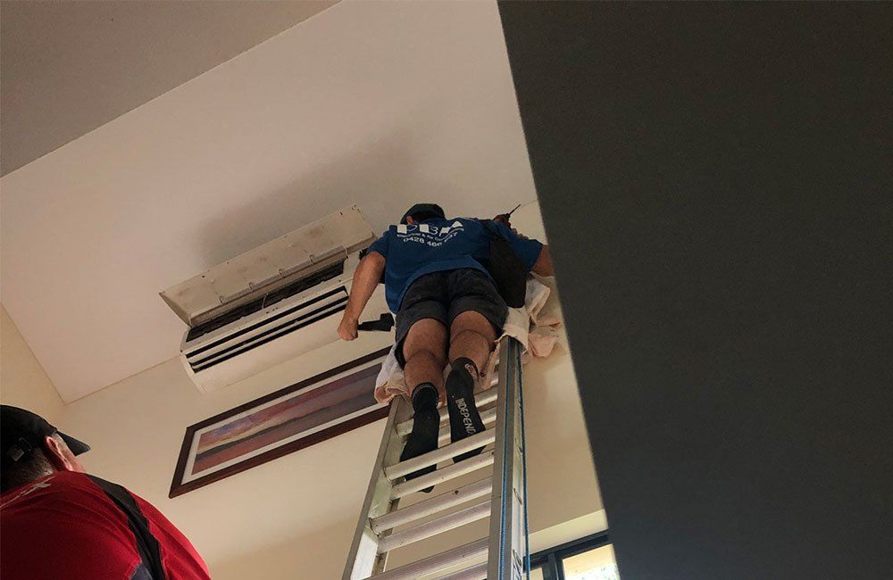 A Professional Fixing An Air Conditioning Unit — Electricians in the Whitsundays, QLD