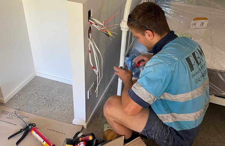 A Man Fixing An Electric Residential Outlet — Electricians in the Whitsundays, QLD