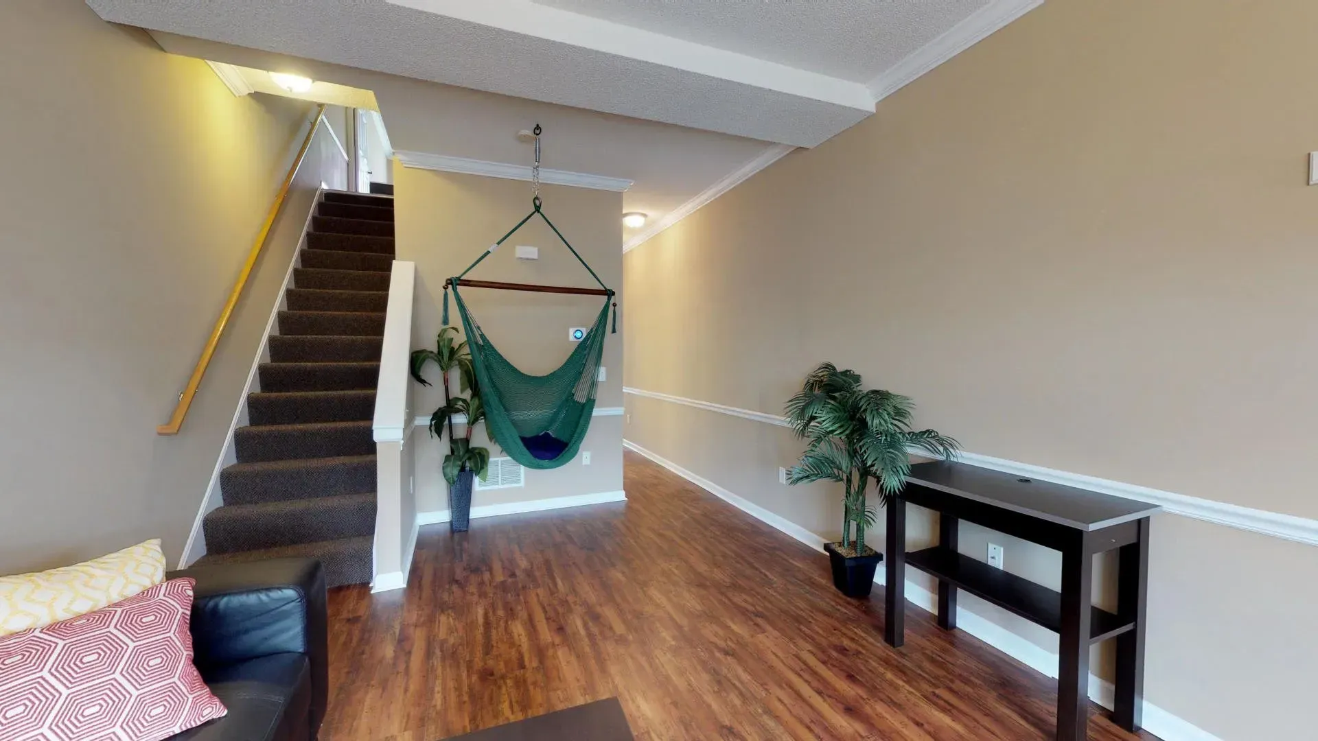 A living room with a hammock hanging from the ceiling and stairs.