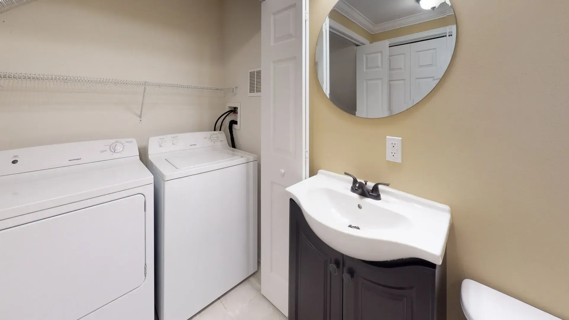 A laundry room with a washer and dryer , sink , toilet and mirror.