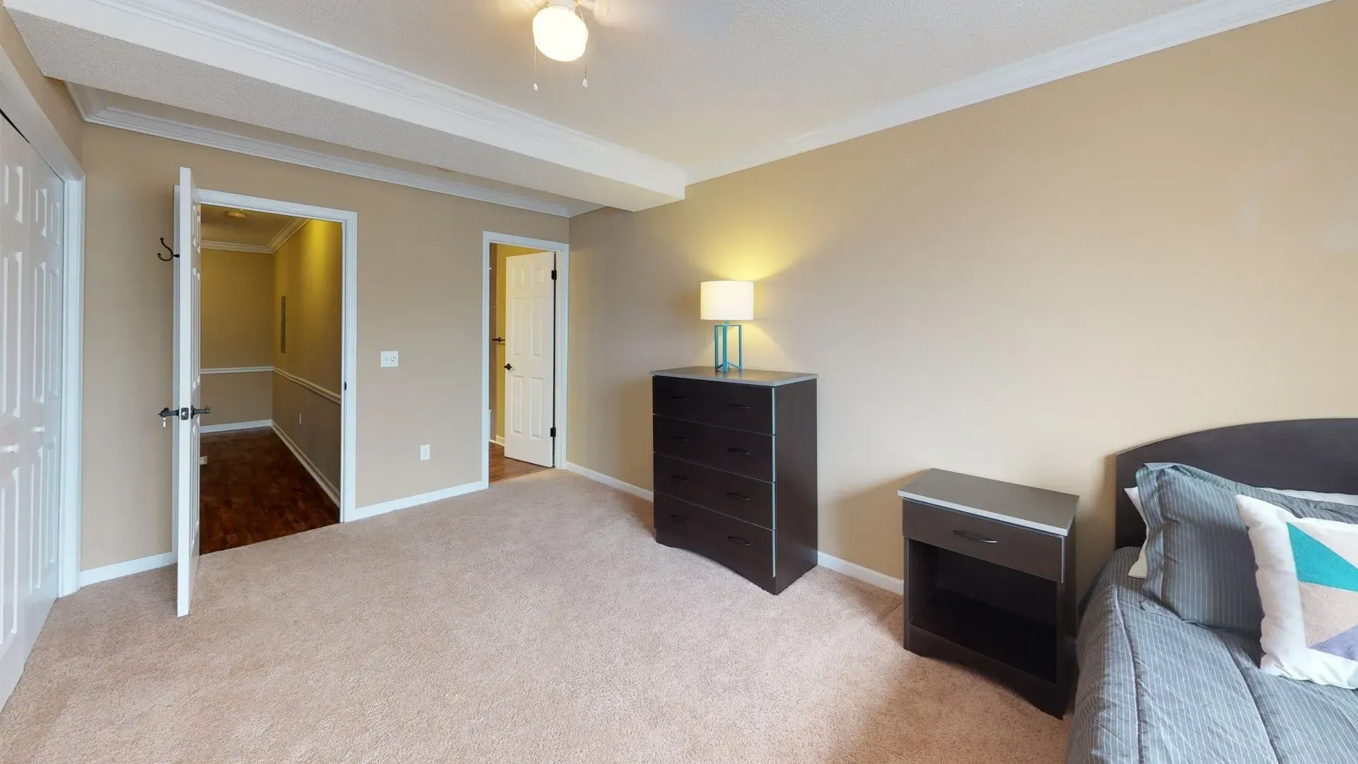 A bedroom with a bed , dresser , nightstand and lamp.