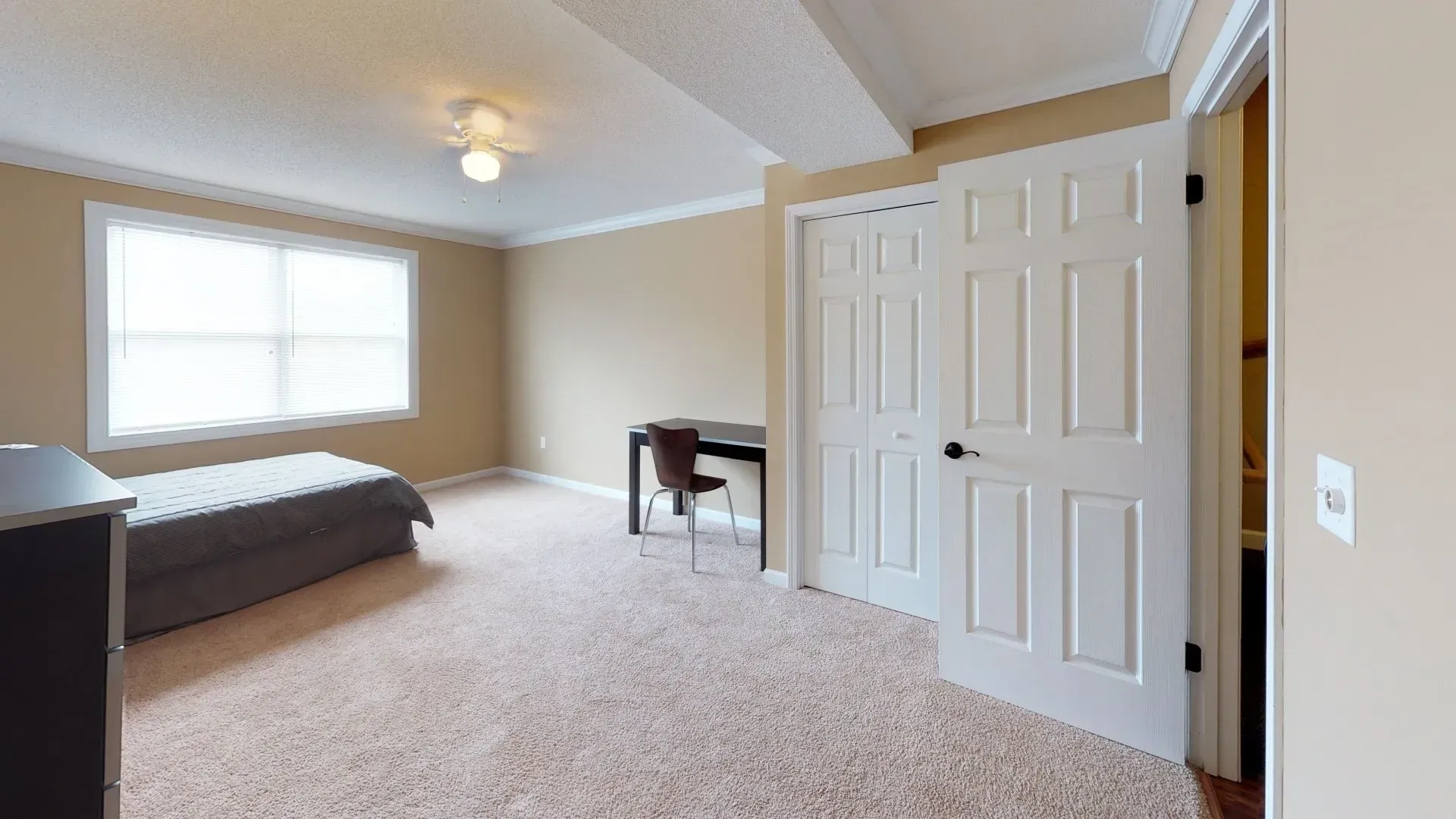 A bedroom with a bed , desk , and window.