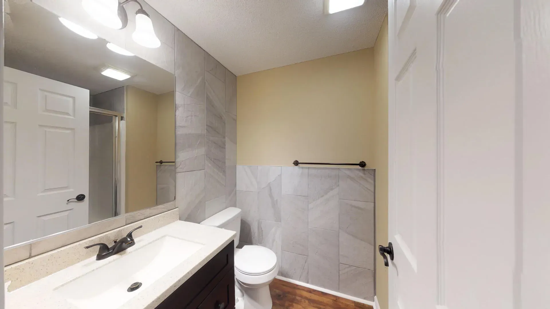 A bathroom with a toilet , sink and mirror.