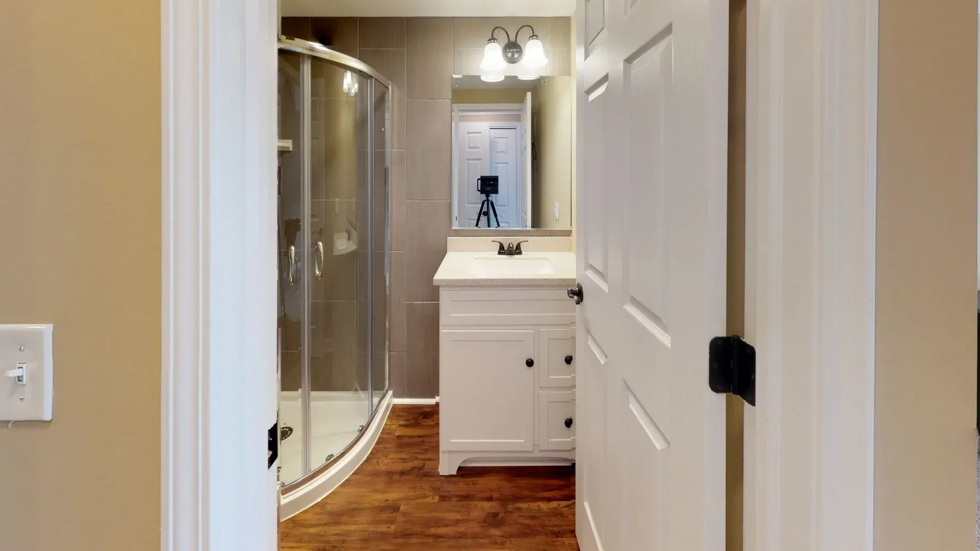 A bathroom with a sink , mirror and shower stall.
