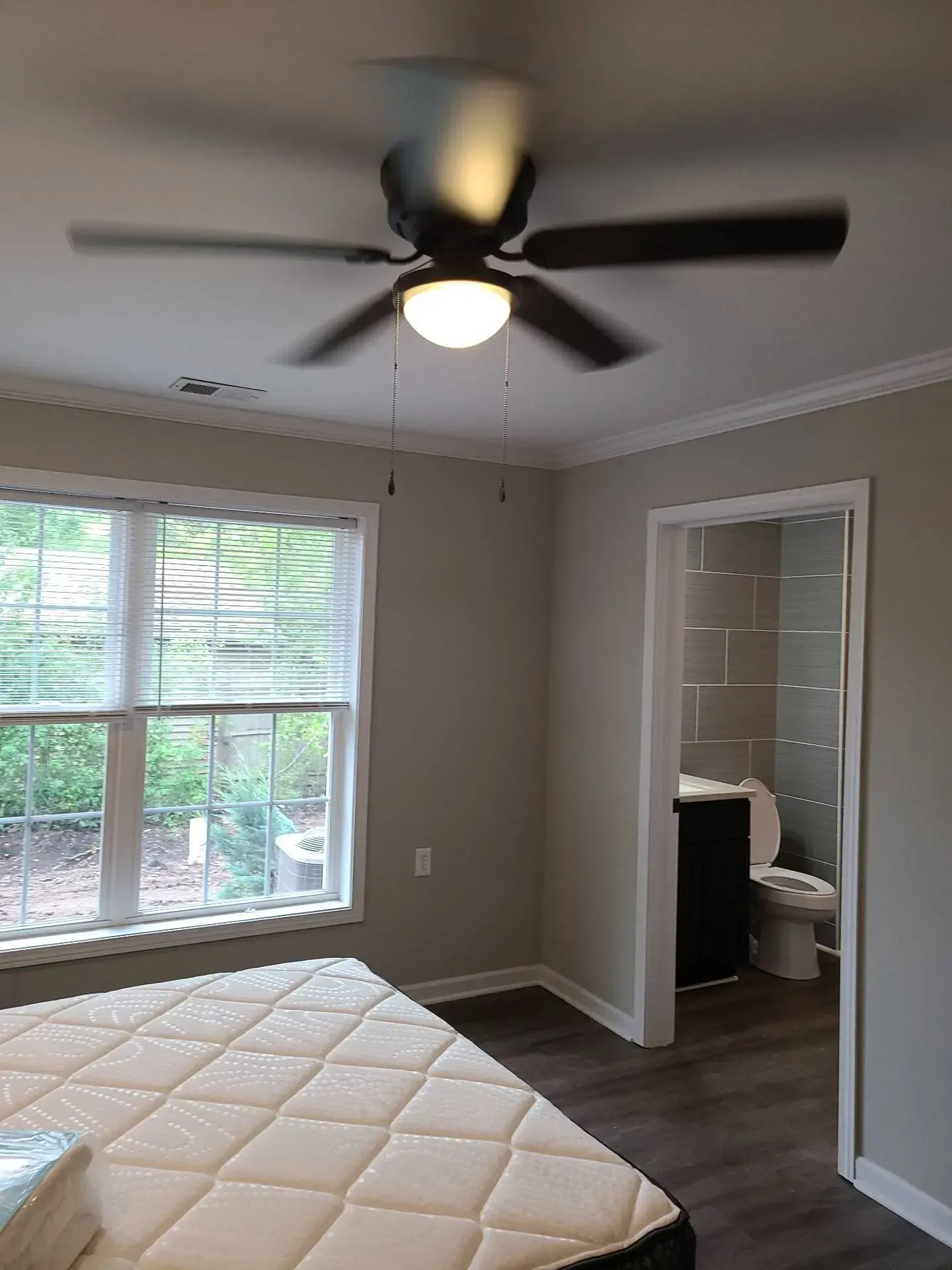 A bedroom with a ceiling fan and a mattress.