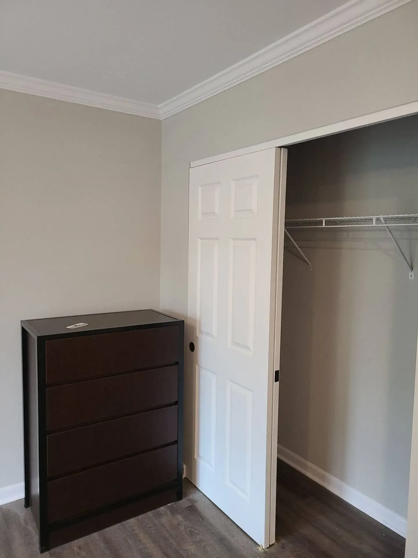 A bedroom with a dresser and a walk in closet.
