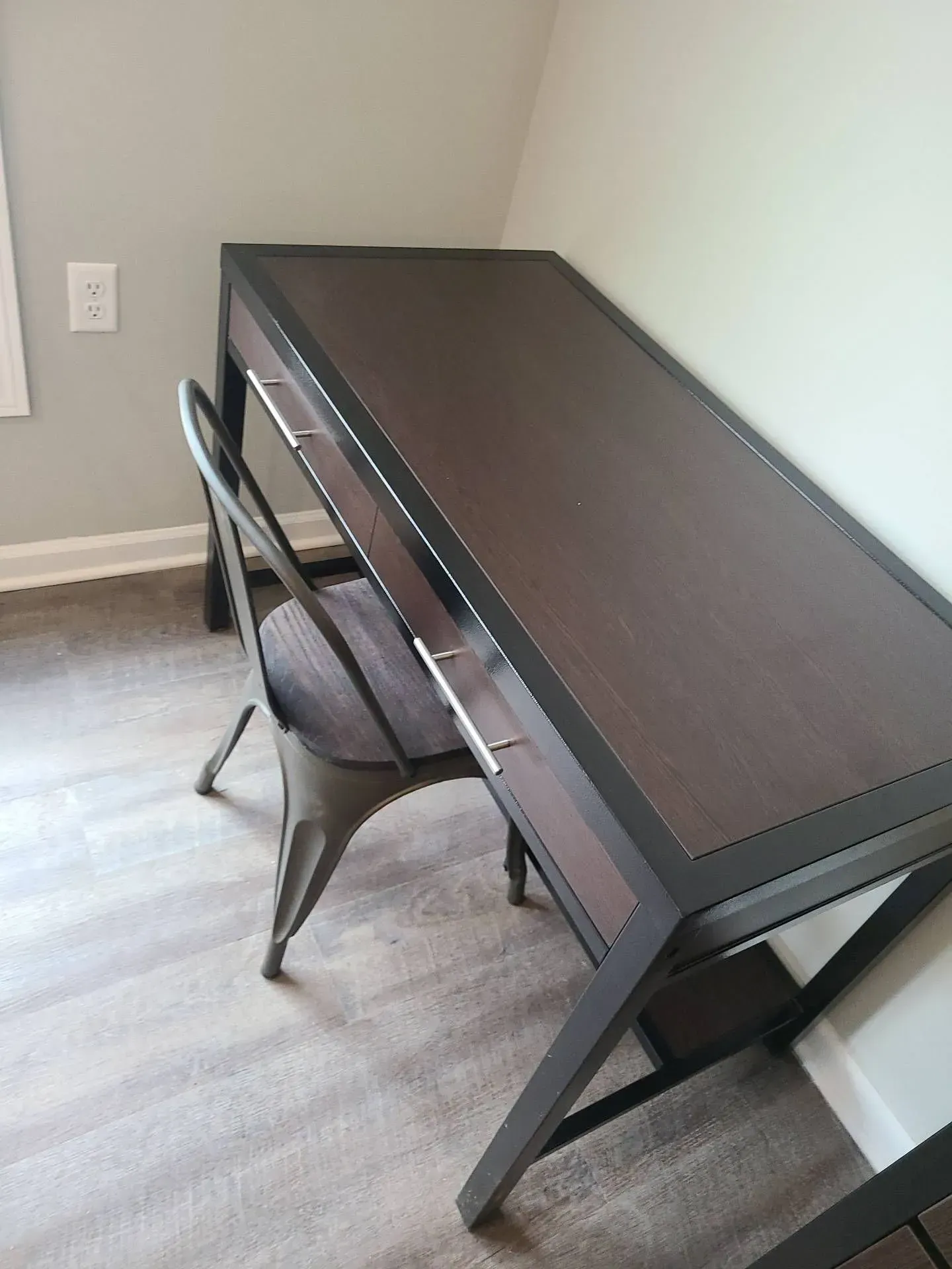 A desk with a chair in a room next to a window.