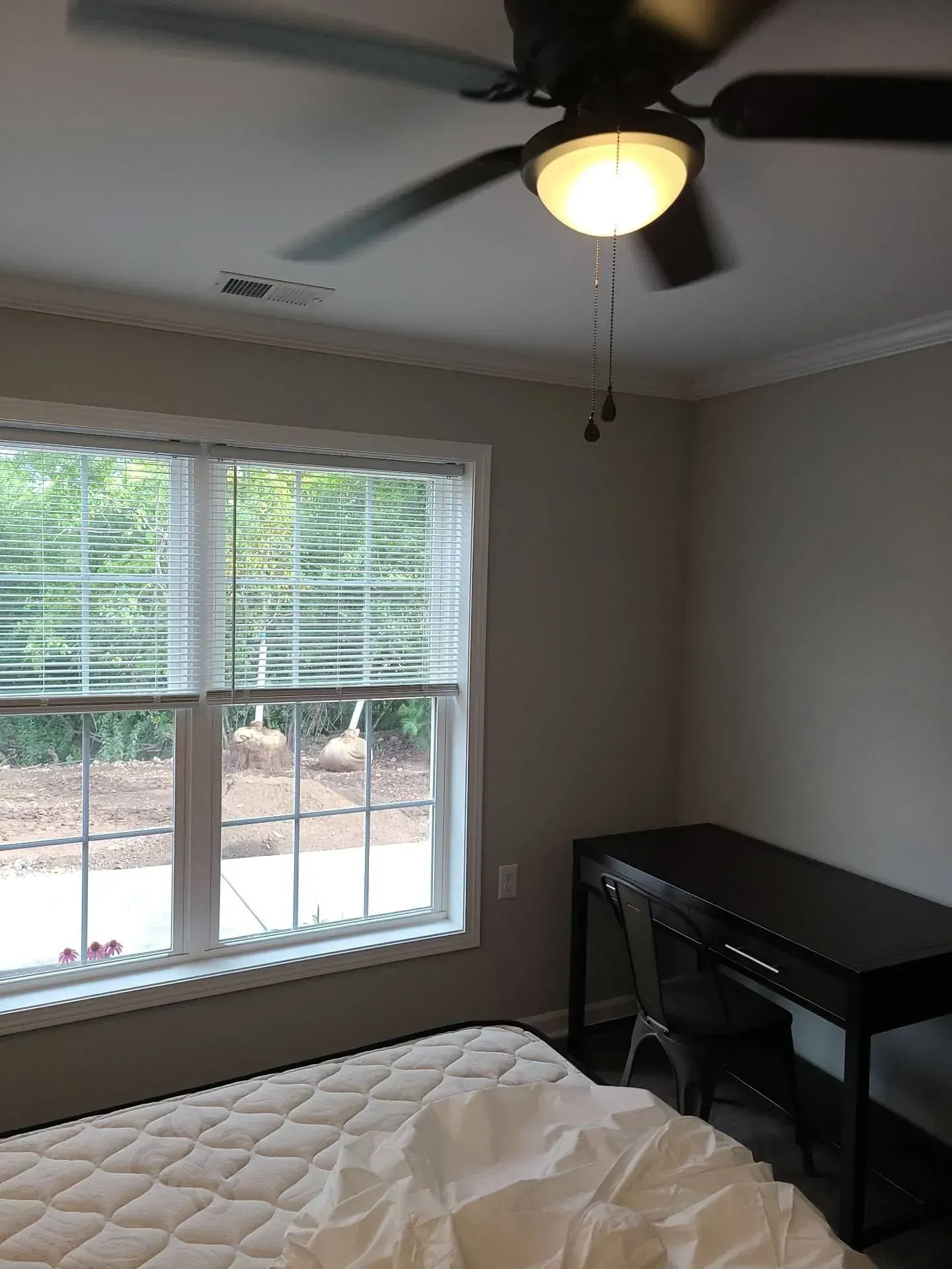 A bedroom with a bed , desk and ceiling fan.