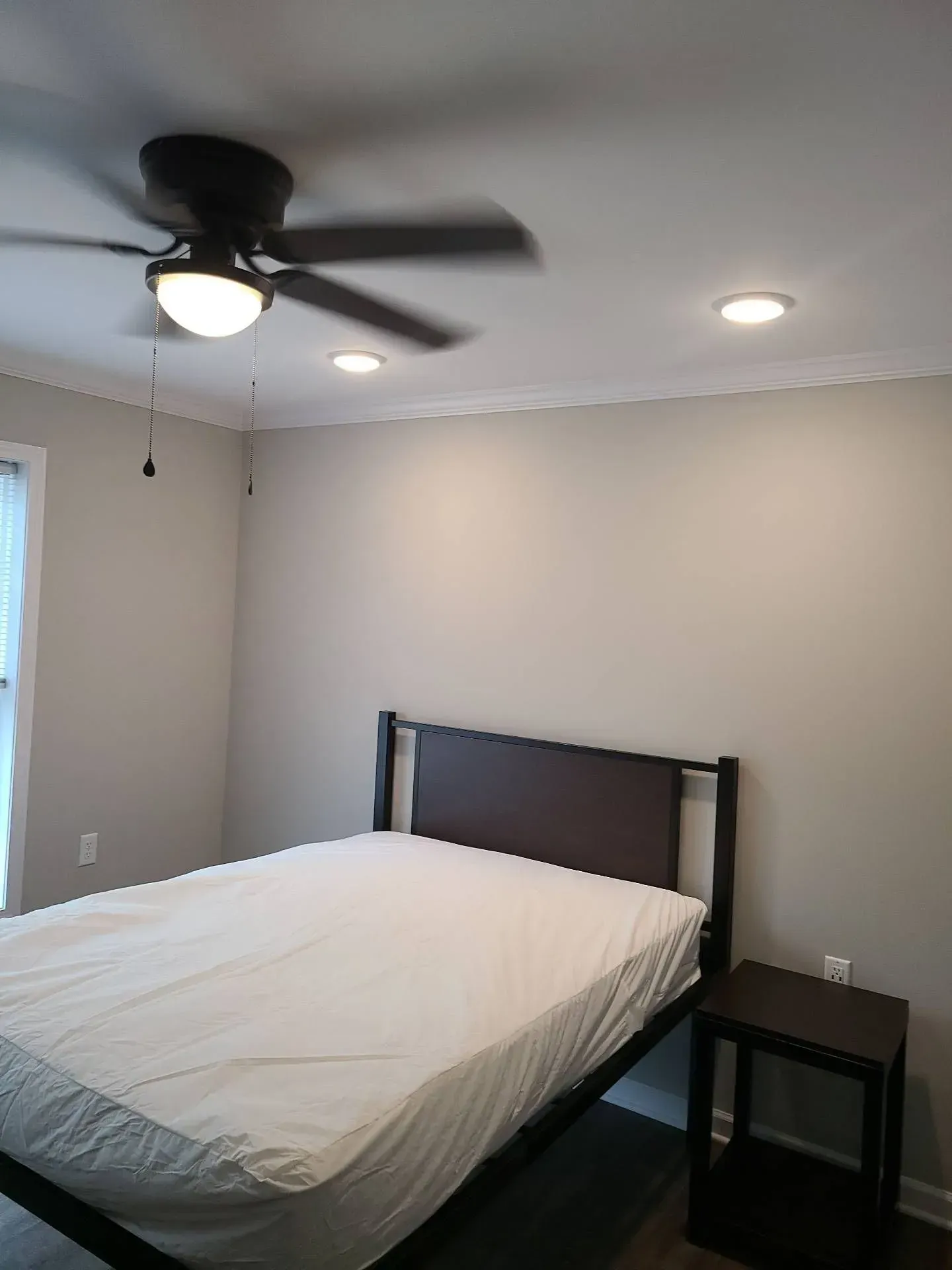 A bedroom with a bed and a ceiling fan