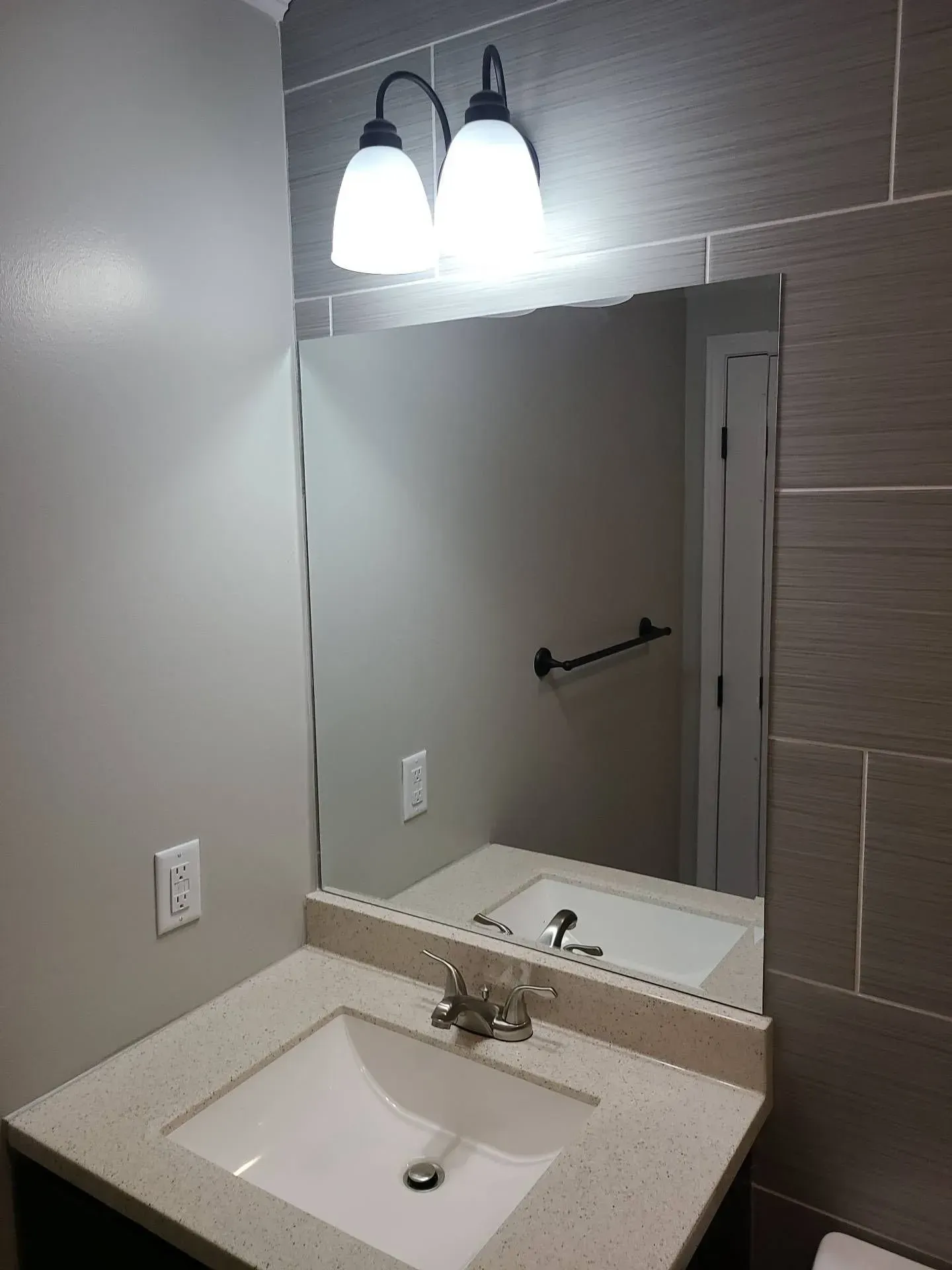 A bathroom with a sink , mirror and light fixtures.