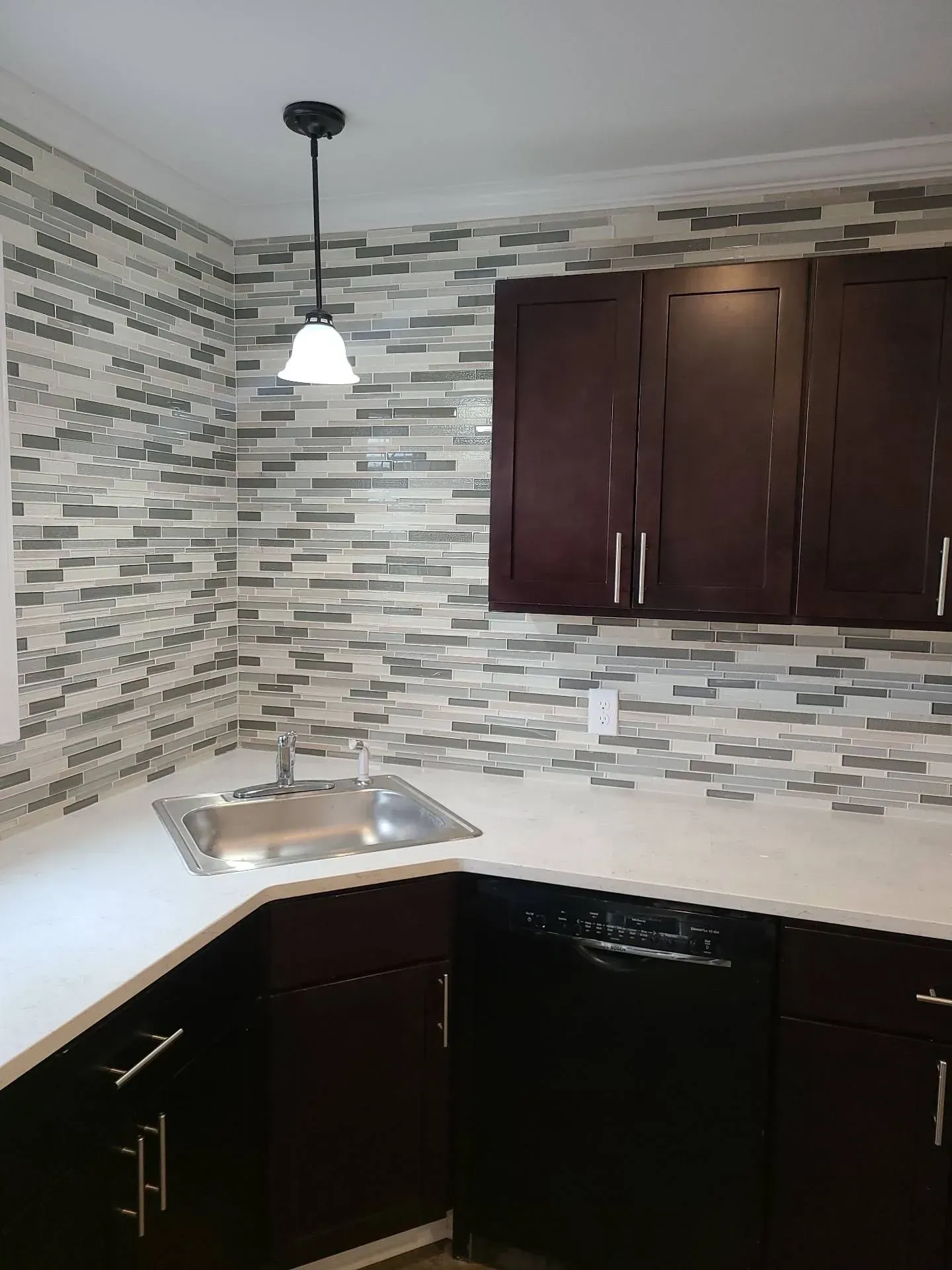 A kitchen with a sink , dishwasher , and cabinets.