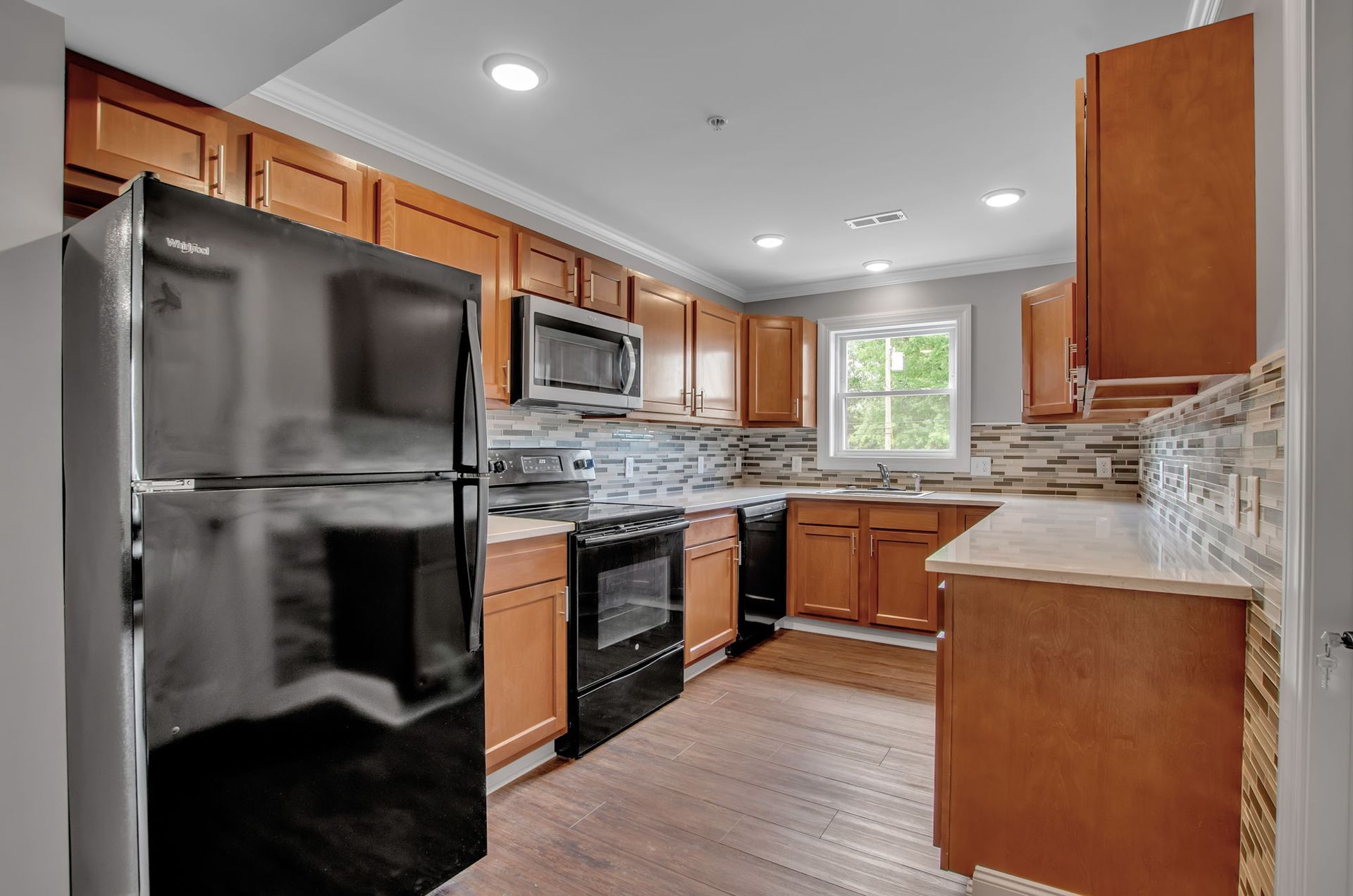 A kitchen with wooden cabinets , stainless steel appliances , and a black refrigerator.
